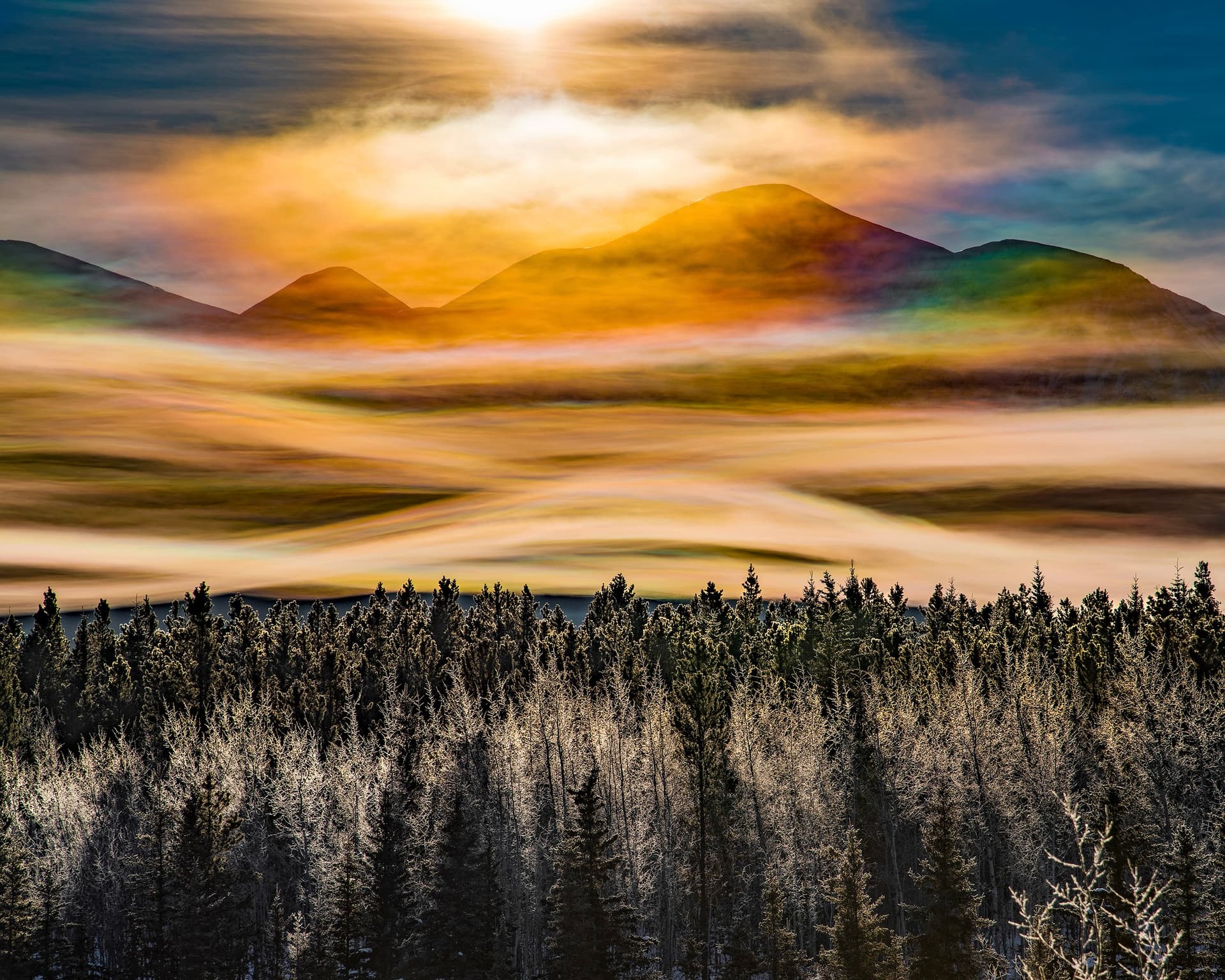 Yukon mountains at dawn with forested slopes and a mist-filled valley